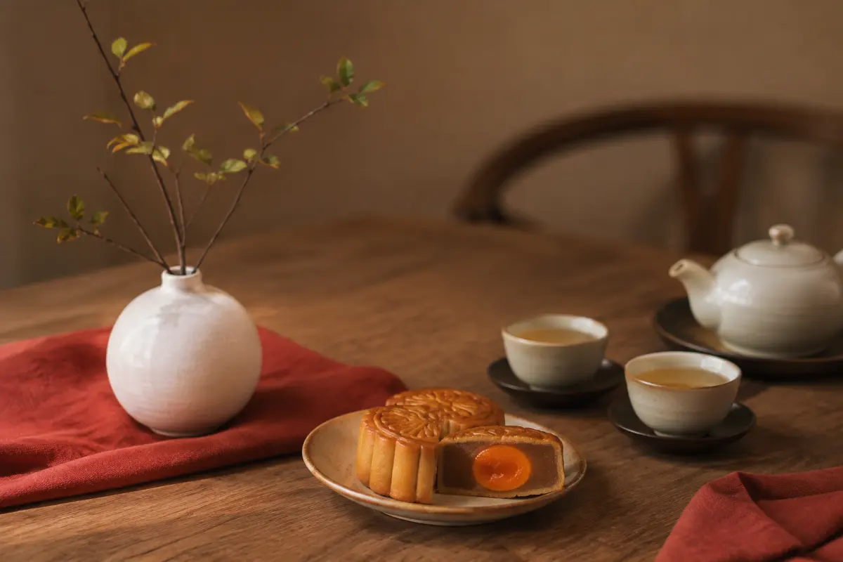 Bình gốm nhỏ cạnh đĩa bánh Trung thu và chén trà
